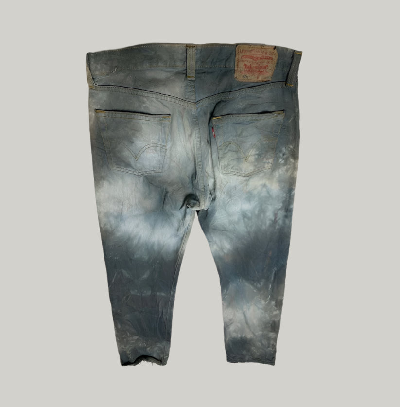 Worn blue jeans with a brand label on a light gray background