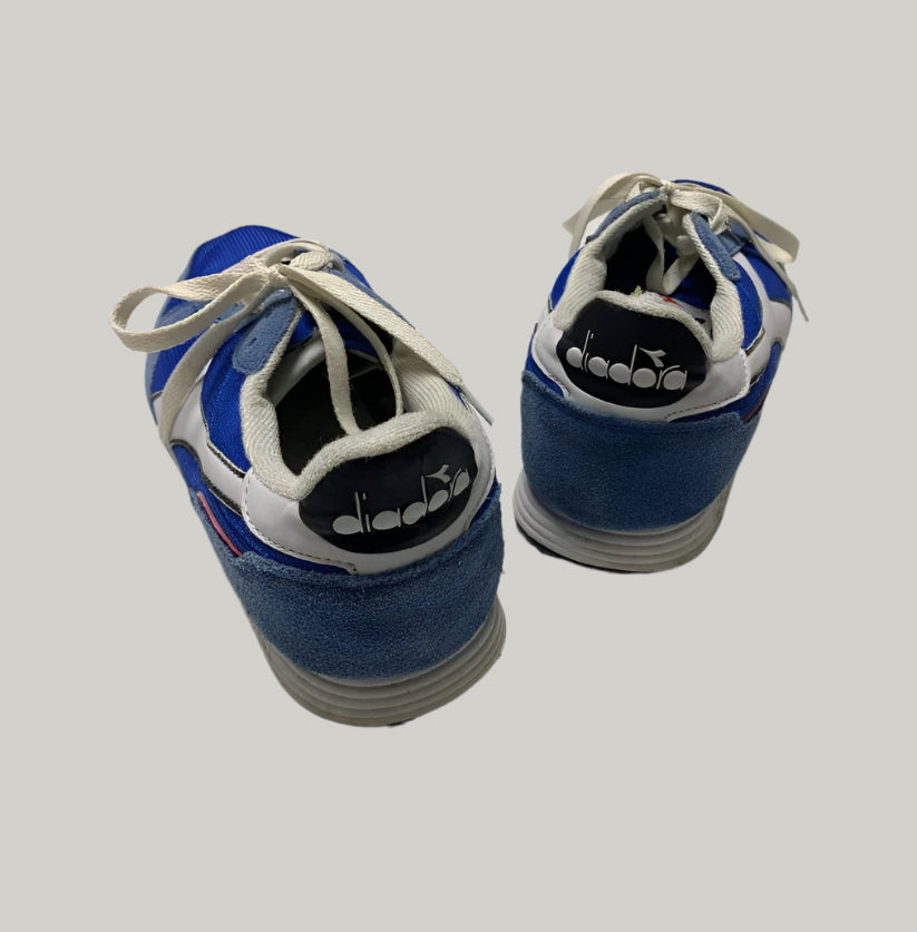 Pair of blue and white sneakers with 'diadora' branding on a light background