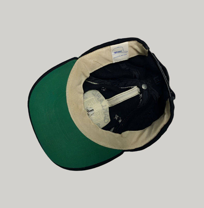 Baseball cap with green front, beige interior, and black brim on a white background