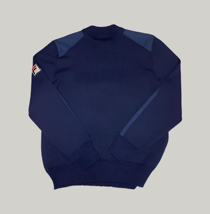 Navy blue sweater with a small logo on the sleeve against a light gray background