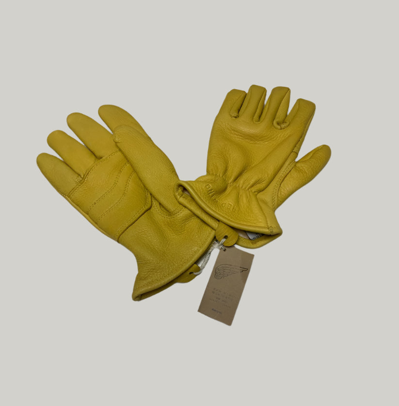 Pair of yellow leather gloves with a tag on a light gray background