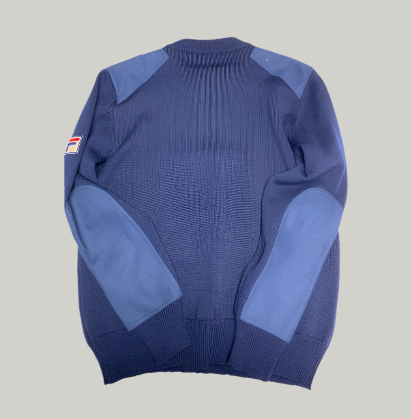 Blue sweater with patch on a light gray background